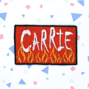 May include: Red embroidered patch with the word "CARRIE" in white lettering with orange flames underneath.