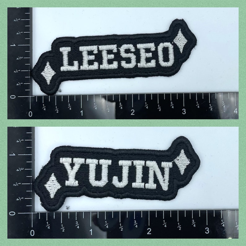 Puede incluir: Dos parches de tela negra con letras blancas. El parche superior dice "LEESEO" y el parche inferior dice "YUJIN".