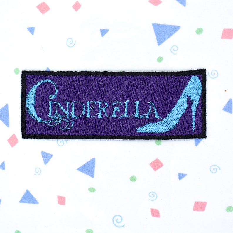 May include: Purple embroidered patch with the word "Cinderella" and a blue glass slipper.