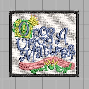 May include: A white embroidered patch with a black border featuring the text "Once Upon A Mattress" in blue and green lettering with a crown above the "O". A pink ribbon with green leaves and a crown is below the text.