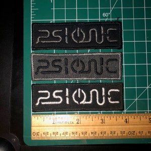 May include: Three black and white embroidered patches with the word "PSIONE" in a stylized font.