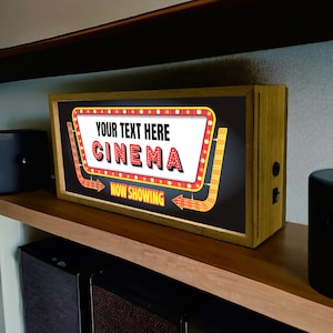 Puede incluir: Un letrero con marco de madera, fondo negro y un marquesina roja y amarilla con el texto "YOUR TEXT HERE CINEMA NOW SHOWING".