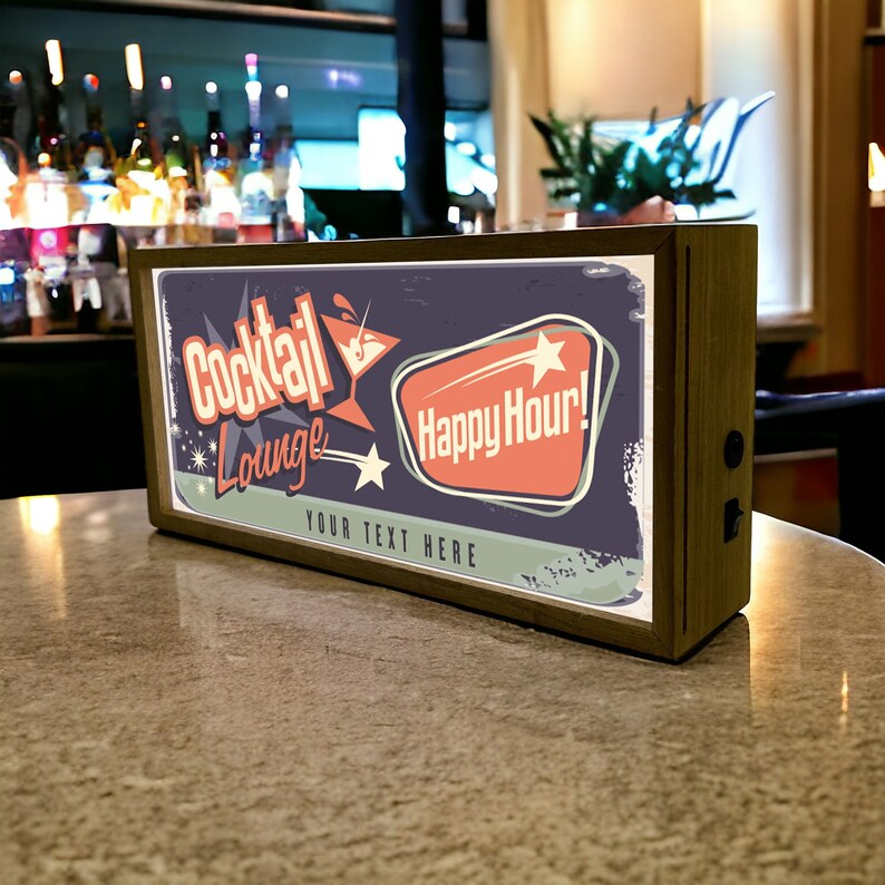 Pu&ograve; includere: Un cartello in legno con un design retr&ograve; che presenta un bicchiere da cocktail e il testo "Cocktail Lounge" e "Happy Hour!" Il cartello ha uno sfondo blu chiaro con accenti arancioni e bianchi. Il testo "Your Text Here" &egrave; stampato sotto il design principale.