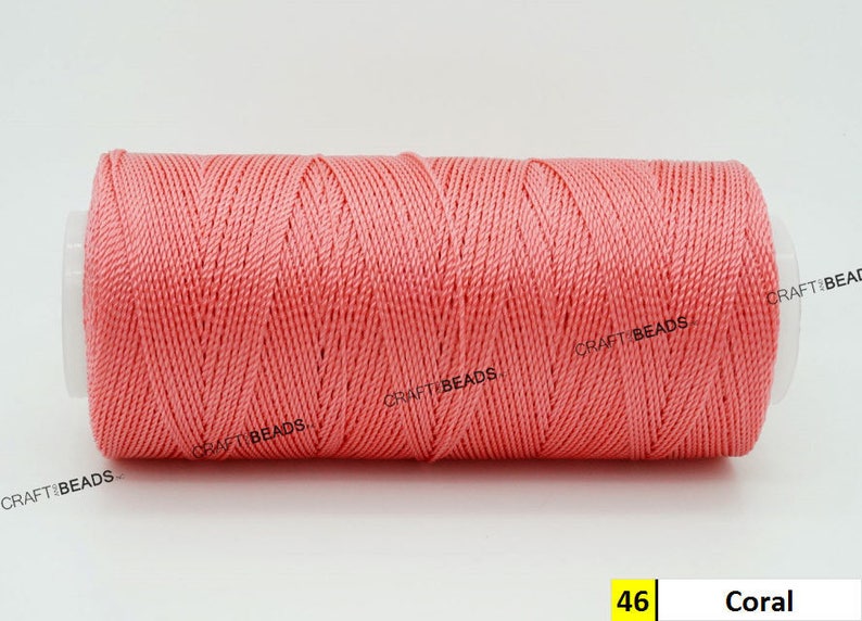 May include: A spool of coral colored thread. The spool is labeled "46 Coral".