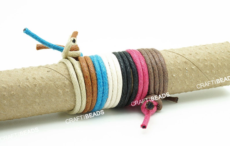 May include: A collection of 10 different colored waxed cotton cords wrapped around a cardboard tube. The cords are all 1 mm thick and are available in a variety of colors, including white, black, brown, blue, and pink. The cords are labeled "CRAFT BEADS".
