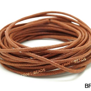 May include: A spool of brown leather cord, approximately 1.5 mm thick, for crafting and jewelry making. The cord is wound tightly and has a smooth, textured surface. The text "CRAFT BEADS" is printed on the cord.