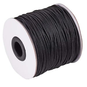 May include: A spool of black nylon cord. The cord is tightly wound around a white cardboard core. The black cord has a slightly textured appearance. The spool is ideal for crafting, jewelry making, or other DIY projects.