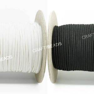 May include: Two spools of elastic cord, one white and one black. The spools are labeled "CRAFTBEADS".