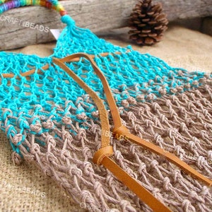 May include: A turquoise and brown crocheted net bag with leather straps. The bag has a rainbow colored handle.