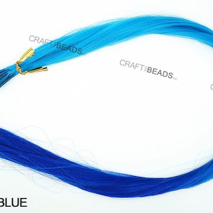 Puede incluir: Una hebra de extensiones de cabello azul con un degradado de azul claro a azul oscuro. Las extensiones de cabello est&aacute;n sujetas a un peque&ntilde;o clip dorado.