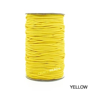 May include: A spool of bright yellow elastic cord. The cord is wound tightly around a cardboard spool. The spool is labeled "Craft Beads".
