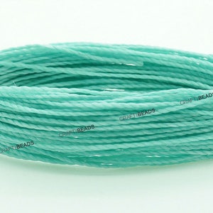 K&ouml;nnte beinhalten: Nahaufnahme einer Spule mit mintgr&uuml;nem gewachstem Baumwollgarn. Das Garn ist gedreht und hat einen dezenten Glanz. Die Spule ist mit "CRAFT BEADS." beschriftet.