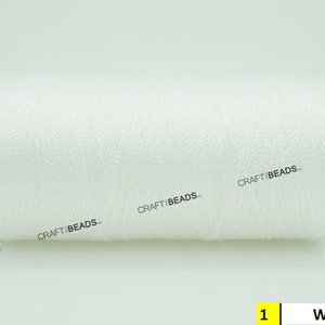 May include: A white spool of thread with the text "CRAFT BEADS" printed on it. The spool is labeled "1 White".