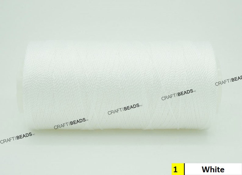 May include: A white spool of thread with the text "CRAFT BEADS" printed on it. The spool is labeled "1 White".