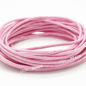 May include: A spool of pink waxed cotton cord. The cord is wound tightly and is ready to be used for crafting projects.