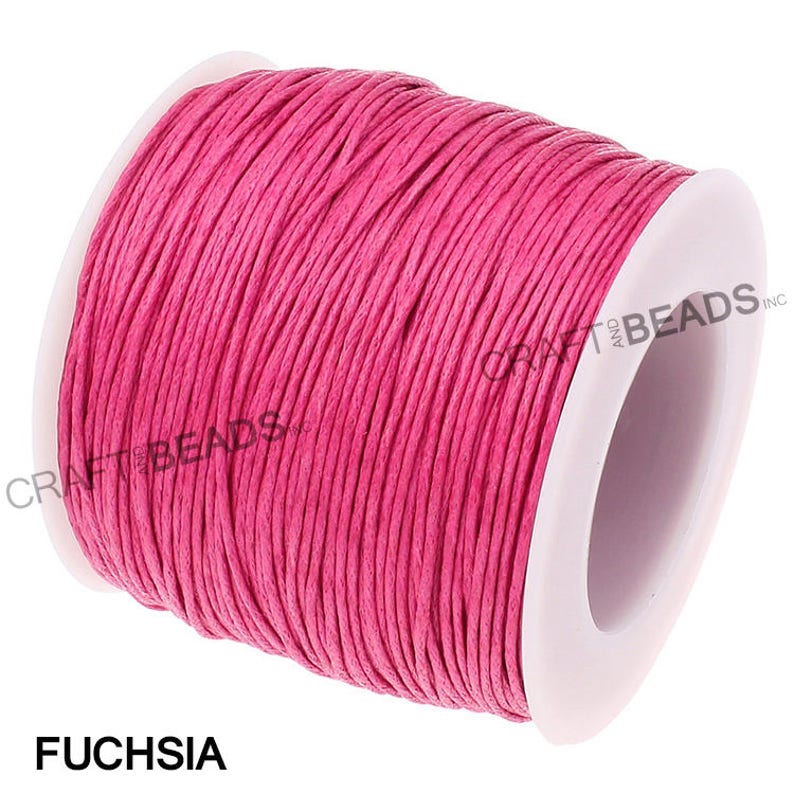 May include: A spool of fuchsia colored waxed cotton cord. The cord is wound around a white plastic spool with the text "CRAFT AND BEADS INC." printed on the side.