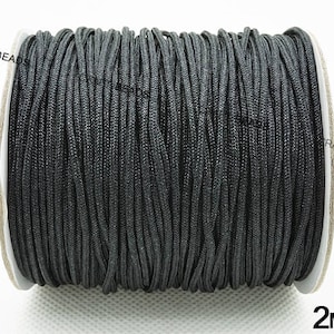 May include: A spool of black 2mm cord. The cord is wound tightly around the spool, which is made of white cardboard. The spool is labeled with the text "CRAFTIBEADS" and "2MM".