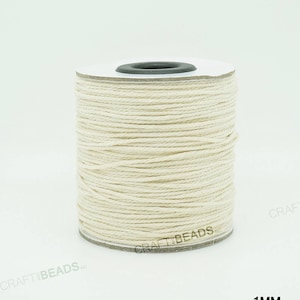 Pu&ograve; includere: Un rotolo di cordoncino in cotone bianco naturale da 1 mm di spessore. Il cordoncino &egrave; avvolto attorno a un rotolo di cartone bianco con un centro in plastica nera.