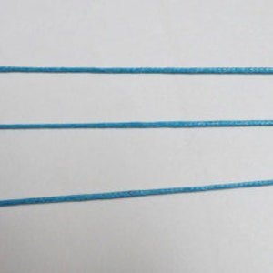 May include: Three strands of light blue cord or string are laid out horizontally on a white surface. A ruler is visible on the right side of the image, with the numbers 16, 17, 18, 19, and 20 visible.