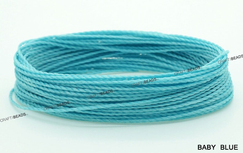 K&ouml;nnte beinhalten: Nahaufnahme einer Spule mit hellblauem gewachstem Garn. Das Garn ist gedreht und hat eine glatte Textur. Der Text "CRAFT BEADS" ist auf der Spule sichtbar.