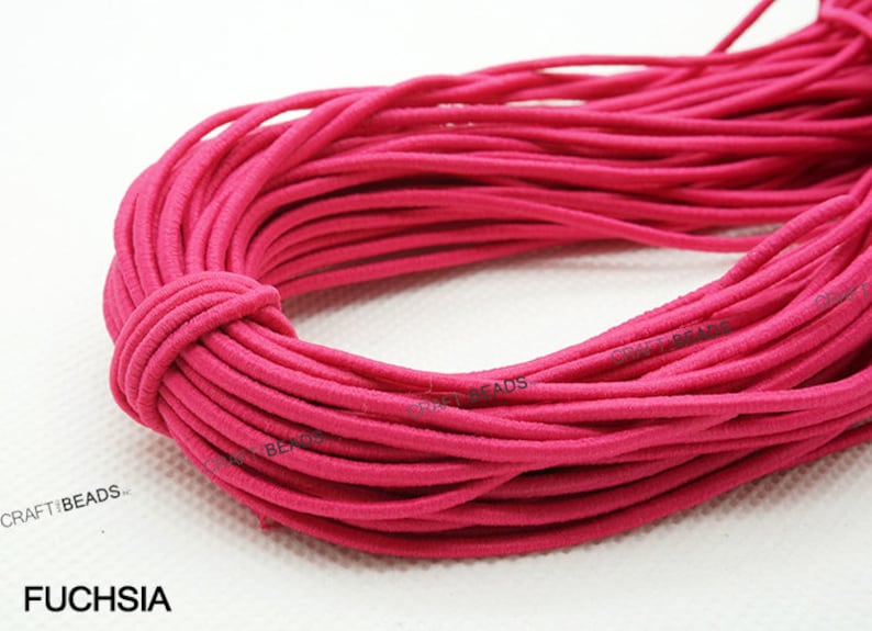 K&ouml;nnte beinhalten: Nahaufnahme einer Spule mit fuchsiafarbenem Gummiband. Das Band ist fest gewickelt und wirkt weich und dehnbar.