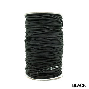 May include: A spool of black elastic cord, wound tightly and ready for use in crafting projects. The cord is labeled "Craft Beads".