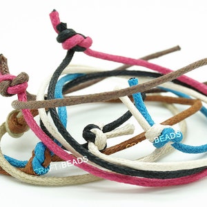May include: Assortment of colorful cotton cords in various colors, including brown, black, white, pink, and blue. The cords are knotted and arranged in a circular pattern.  CRAFT BEADS is visible on the cords.