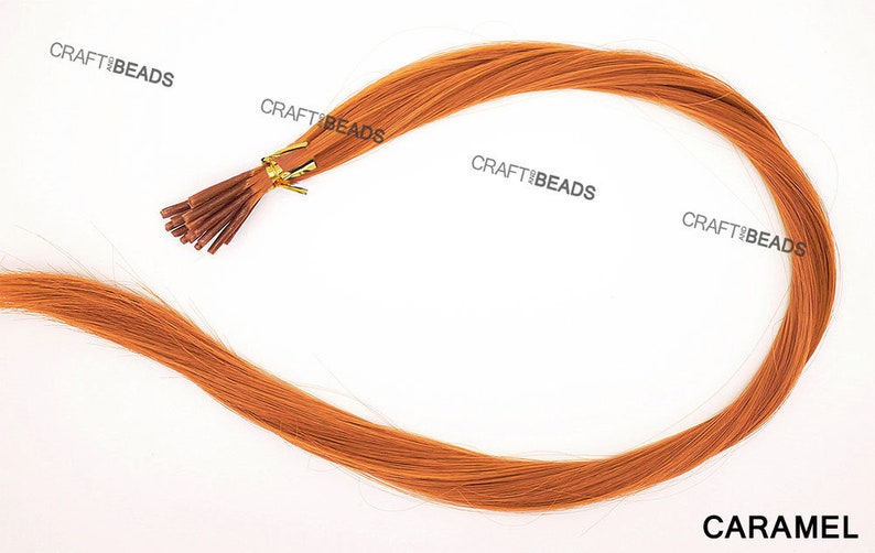 Puede incluir: Una hebra de extensiones de cabello humano de color caramelo con microanillos unidos. El cabello es liso y parece tener unos 45 cm de largo.