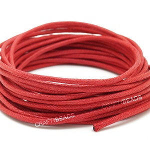 May include: A spool of red waxed cotton cord. The cord is wound tightly and is ready to be used for crafting projects.