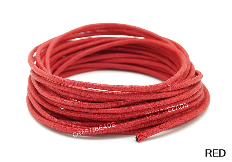 May include: A spool of red waxed cotton cord. The cord is wound tightly and is ready to be used for crafting projects.