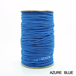 May include: A spool of bright blue elastic cord, wound tightly. The cord is smooth and appears to be made of a soft material. The spool is labeled "CRAFT BEADS" and the color is "AZURE BLUE".
