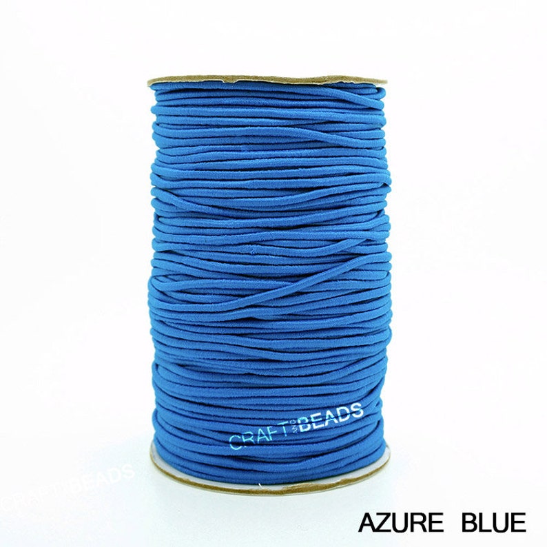 May include: A spool of bright blue elastic cord, wound tightly. The cord is smooth and appears to be made of a soft material. The spool is labeled "CRAFT BEADS" and the color is "AZURE BLUE".