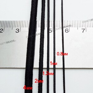 K&ouml;nnte beinhalten: F&uuml;nf schwarze Gummib&auml;nder in verschiedenen St&auml;rken, gemessen in Millimetern, auf einem wei&szlig;en Lineal. Die B&auml;nder haben einen Durchmesser von 0,8 mm, 1 mm, 1,2 mm, 2 mm und 4 mm.