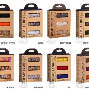 Puede incluir: Tres carretes de cuerda de cáñamo natural en varios colores, incluyendo naranja, negro y gris, empaquetados en una caja de cartón marrón con el nombre de la marca "Hemptique" y el texto "HEMP CORD 100% natural" impreso en la parte delantera. La caja también incluye el texto "Ginger Spice" impreso debajo de la imagen.