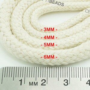 May include: Close-up of white cotton cord in four different sizes, measured in millimeters, with a ruler for reference. The cord is braided and has a textured surface.