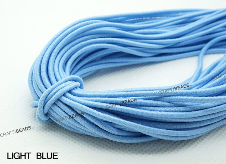 K&ouml;nnte beinhalten: Nahaufnahme einer Spule mit hellblauem Gummiband. Das Band ist fest gewickelt und bereit f&uuml;r Bastelarbeiten.