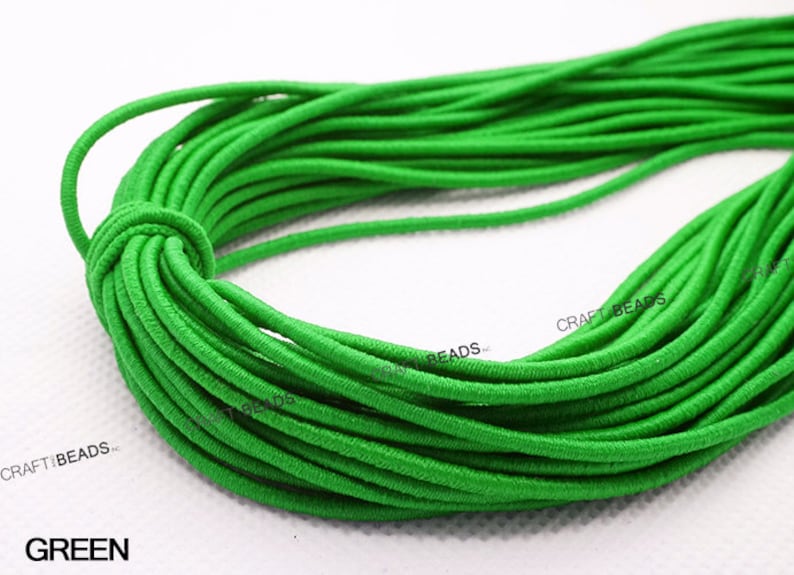 K&ouml;nnte beinhalten: Nahaufnahme einer Spule mit leuchtend gr&uuml;nem Gummiband. Das Band ist fest gewickelt und scheint aus einem weichen, dehnbaren Material zu bestehen. Der Text "CRAFT BEADS" ist auf der Spule sichtbar.