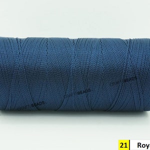 May include: A spool of royal blue waxed cord, a type of thread used for crafts and jewelry making.