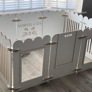 May include: White wooden cat playpen with a scalloped top and a cat silhouette with the words "MARVEL CATS" on the front.