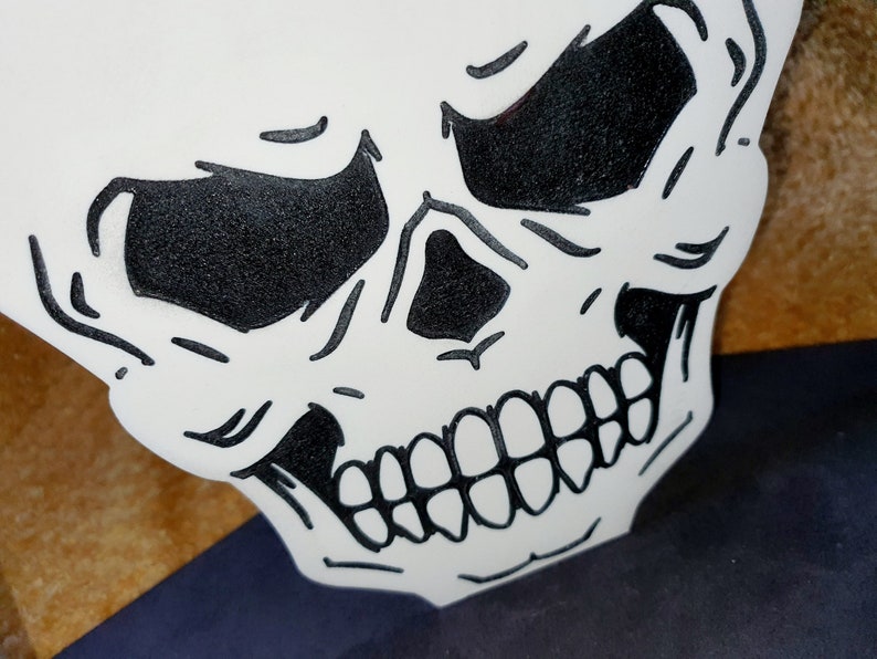 May include: A white skull with black eyes and teeth. The skull is drawn in a cartoon style and has a menacing expression.