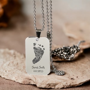 May include: Silver necklace with a rectangular tag featuring a baby's footprint and the inscription "Sarah Smith 8.6.2023".