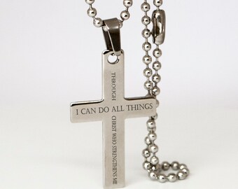 Puede incluir: Collar de cadena de plata con un colgante de cruz de plata. La cruz tiene la inscripción "Todo lo puedo en Cristo que me fortalece".