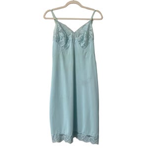 May include: A light blue slip with lace trim at the neckline and hem. The slip is sleeveless and has a V-neck.