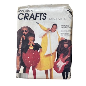May include: A vintage McCall's Crafts pattern packet featuring costume designs. The costumes include a banana, strawberry, and a guitar. The packet has text in English and French, with price tags and size information.