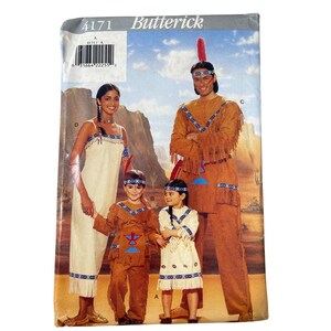 May include: A Butterick sewing pattern featuring Native American-style costumes. The pattern includes designs for adults and children, with fringed tops, pants, and dresses. The costumes are in shades of brown, tan, and white, with blue and red accents.