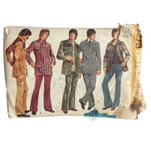 May include: A vintage Simplicity sewing pattern envelope, number 5273, featuring illustrations of five different jacket and trouser outfits. The text on the envelope indicates a size 46, chest 46, and waist 42. The paper envelope is worn and torn.