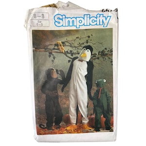 May include: Simplicity sewing pattern for children's costumes. The pattern features a penguin, monkey, and frog costume. The package is white with blue text and includes size information. The costumes are shown in a fall setting with pumpkins and leaves.