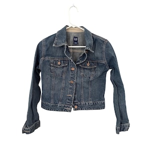 May include: A blue denim jacket with long sleeves, a collared neckline, and button closures. The jacket has two chest pockets and two side pockets. The brand tag is visible. The jacket is hanging on a white hanger.