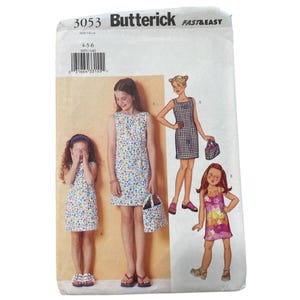 May include: Butterick sewing pattern 3053 for a sleeveless dress in sizes 4-5-6. The envelope features illustrations of dresses in floral and checkered prints, along with a matching bag. The text includes the brand name Butterick, pattern number 3053, and the label FAST&EASY.