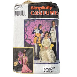 May include: A Simplicity Costumes sewing pattern envelope, number 9229, featuring illustrations of various medieval-style outfits. The package displays individuals wearing a gold and purple tunic, a long cream gown, a purple cape, and a pink dress.